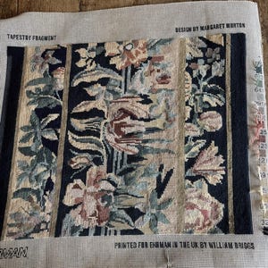 May include: A tapestry fragment featuring a floral pattern in blue, beige, and pink hues. The design is bordered by vertical black and beige stripes. The text "TAPESTRY FRAGMENT" and "DESIGN BY MARGARET MORTON" are visible.