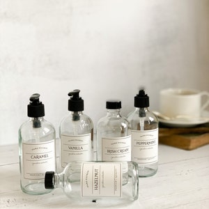 May include: Five clear glass bottles with black pump tops and labels. The labels have the words "Hand Poured" and different scents: Caramel, Vanilla, Irish Cream, Peppermint, and Hazelnut.