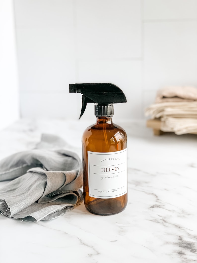 May include: A brown glass bottle with a black spray nozzle filled with Thieves Signature essential oil blend. The bottle has a white label with the text "HAND POURED", "THIEVES", "Signature mixture", "PREMIUM QUALITY".