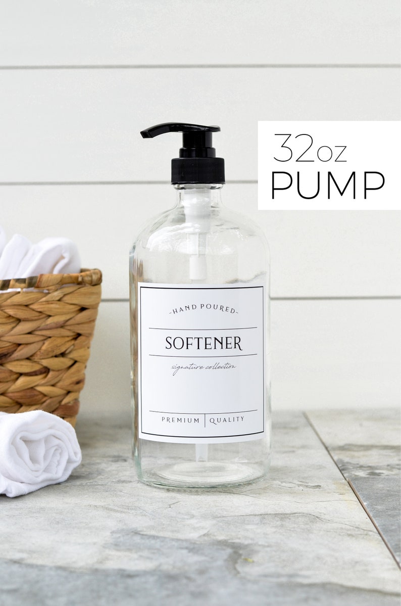 May include: A clear glass bottle with a black pump dispenser filled with liquid. The bottle has a white label that reads "Hand Poured - Softener - Signature Collection - Premium Quality". The bottle is labeled as 32 oz Pump.