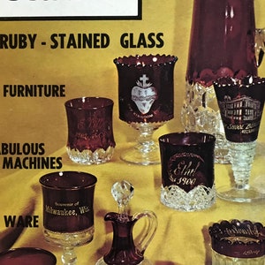 Può includere: Una copertina della rivista "The Antiques Journal" con il titolo "About Ruby-Stained Glass". L'immagine mostra vetreria color rubino, tra cui calici, una brocca e una piccola caraffa, tutte con disegni dettagliati e incisioni.