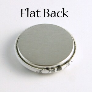 May include: The back of a round button with a flat, silver surface. The text "Flat Back" is printed above the button.