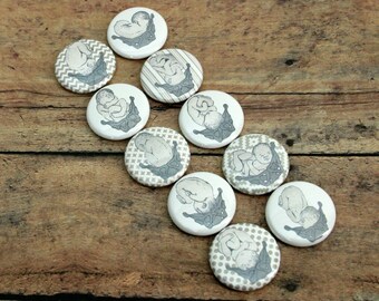 May include: Ten round white buttons with a gray and white patterned design. Each button features a black and white illustration of a baby in a fetal position.