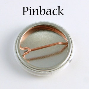 May include: The back of a round button with a silver metal backing and a copper pinback.