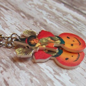 May include: A pair of Halloween-themed earrings featuring a vintage illustration of a witch riding a broomstick with a pumpkin. The earrings are made of white plastic with a red, orange, and yellow color scheme.