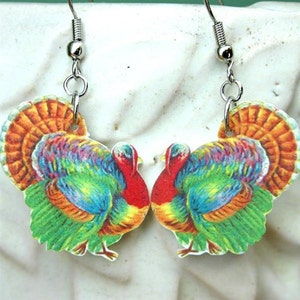 May include: A pair of dangle earrings featuring a colorful vintage illustration of two turkeys facing each other. The earrings are made of metal with silver hooks.