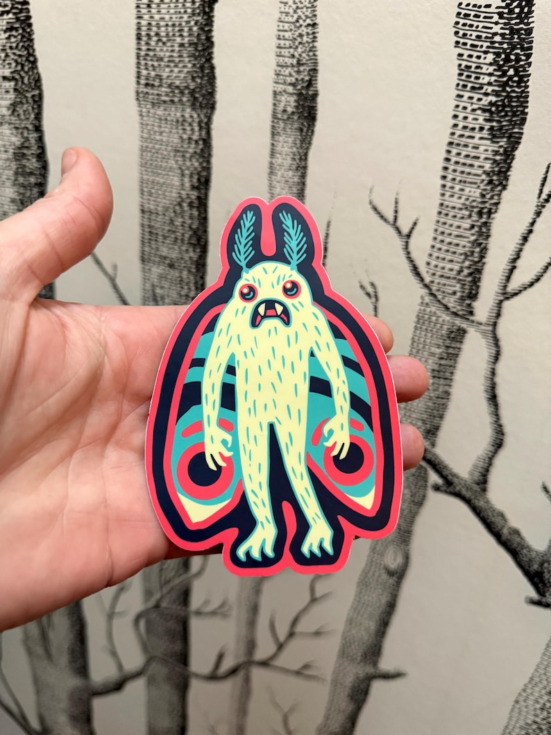 May include: A sticker of a cartoon monster with a yellow body, blue wings, and red eyes. The monster has a furry body and is standing with its wings spread out.