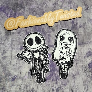 May include: Two embroidered iron-on patches featuring characters from the movie The Nightmare Before Christmas. The patch on the left is black and white and depicts Jack Skellington. The patch on the right is black and white and depicts Sally. The patches are on a light brown wooden surface with the text "@Fashionably Twisted" written on it.