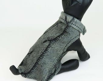 May include: A black dog mannequin wearing a gray and black patterned fleece dog sweater.