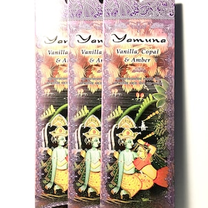 May include: Three packs of incense sticks with a purple and white floral design. The incense is labeled "Yamuna Vanilla, Copal & Amber" and features a colorful illustration of a couple. The text "Prabhuji's Gifts Stick Incense" is printed on the bottom of the packaging.