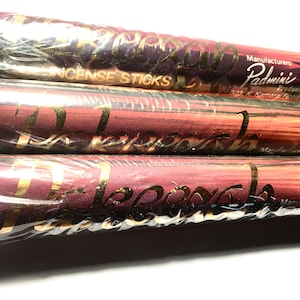 May include: Three incense stick packages wrapped in clear plastic. The packages have a burgundy and gold color scheme with the word "Padmini" and "Incense Sticks" printed on them. The background is white.