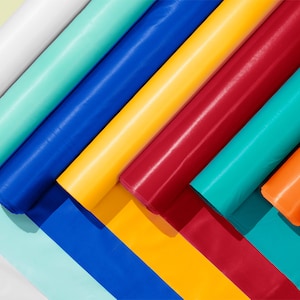 May include: A collection of rolled up colorful tissue paper in shades of white, turquoise, blue, yellow, red, teal, orange, and red. The tissue paper is arranged in a fan shape.