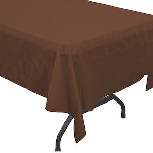 May include: A brown plastic tablecloth. The tablecloth is rectangular and has a smooth surface. It is draped over a table with black metal legs.