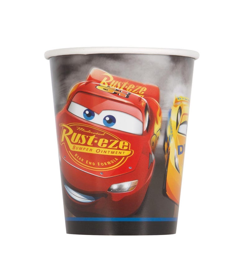 May include: A paper cup featuring a red race car with the text "Rust-eze" and "Bumper Ointment". The cup has a white rim and a black base, with a smoky background and a yellow race car.