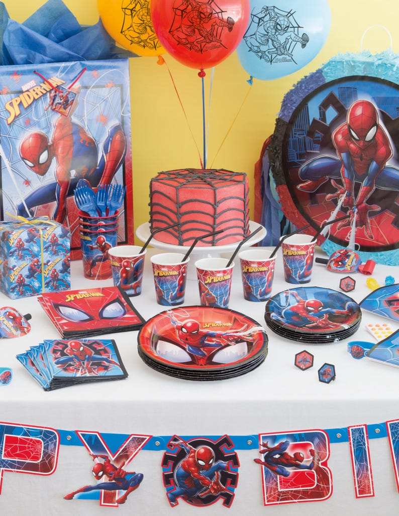 Op de afbeelding: Een rode en blauwe Spider-Man-thema verjaardagsfeesttafel met een taart, borden, bekers, servetten, ballonnen, een pi&ntilde;ata en een banner.