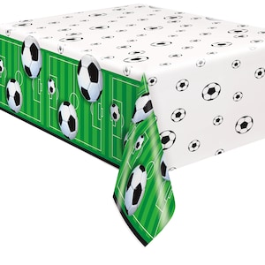 May include: Green and white plastic tablecloth with a soccer field design and soccer balls. The tablecloth has a white background with black soccer balls and a green border with a soccer field design.