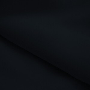 May include: A close-up shot of a folded, dark navy fabric. The fabric has a smooth texture and is folded at a diagonal angle, creating a play of shadows and highlights. The overall effect is a minimalist, elegant presentation.