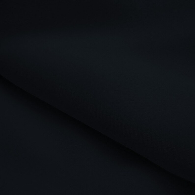 May include: A close-up shot of a folded, dark navy fabric. The fabric has a smooth texture and is folded at a diagonal angle, creating a play of shadows and highlights. The overall effect is a minimalist, elegant presentation.