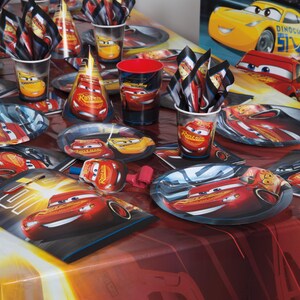 May include: A party table setting featuring Lightning McQueen from the Cars movie. Includes plates, cups, napkins, and party hats. The color scheme is red, yellow, and black, with images of the race car. Perfect for a child's birthday party.