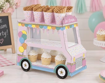 May include: A two-tiered cardboard display stand shaped like an ice cream truck. The pink and blue truck features a graphic of balloons, a scalloped banner, and the text "Ice Cream" on the roof. It holds waffle cones on the top shelf and cupcakes.