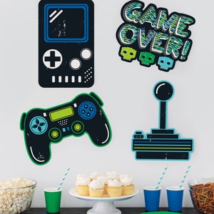 May include: A set of four black and blue game-themed wall decals. The decals feature a retro video game console, a joystick, a modern game controller, and the words "Game Over!" in a pixelated font.
