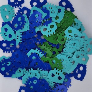 May include: A pile of blue, green, and turquoise paper cutouts in the shape of a pixelated robot.