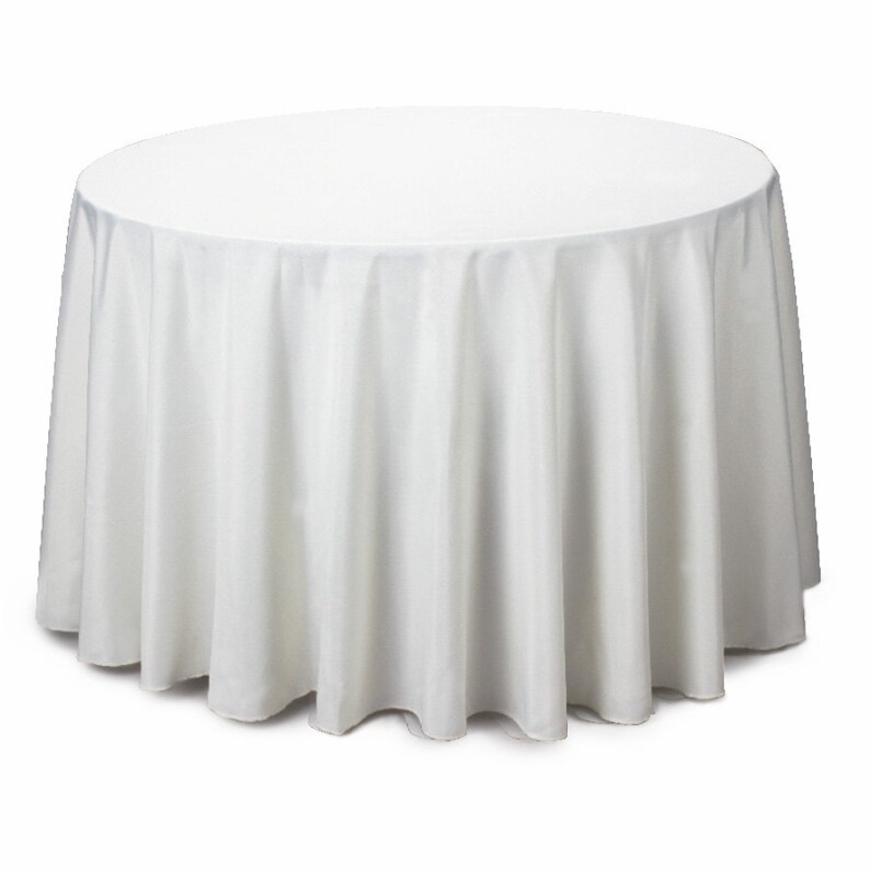 May include: A white, round tablecloth. The fabric drapes to the floor, creating soft folds. The tablecloth is made of a smooth, opaque material, suitable for formal events or everyday use. The table covering is a solid white color.