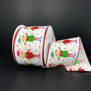 May include: White burlap ribbon with a red, green, and blue elf design. The ribbon has a red wired edge.