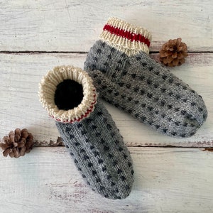 May include: A pair of gray knitted socks with white and red trim. The socks have a small, repeating pattern of black dots.