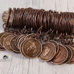May include: A collection of vintage farthing coins, each with a bird design, are suspended from copper wire. The coins are attached to a wooden dowel with copper wire rings. The coins are a bronze color.