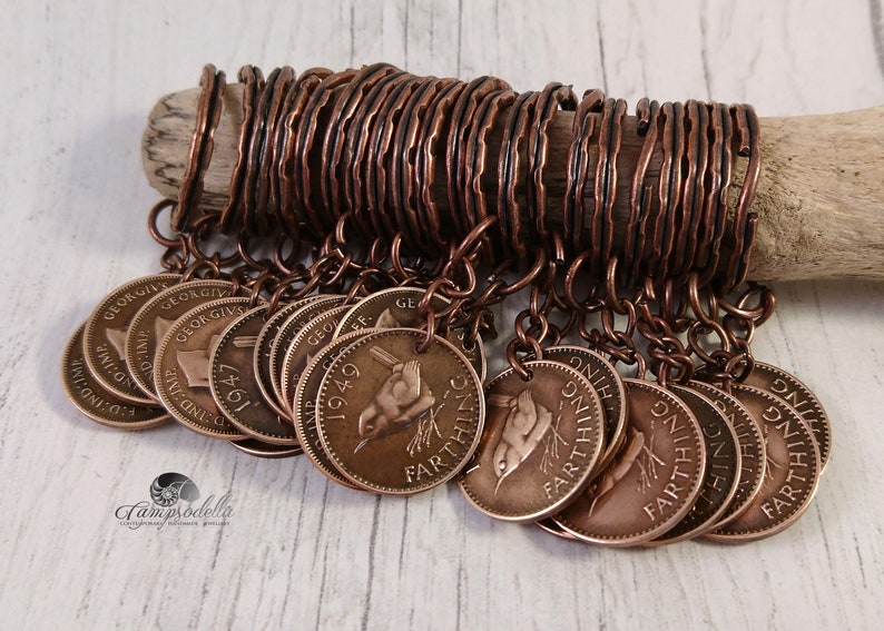 May include: A collection of vintage farthing coins, each with a bird design, are suspended from copper wire. The coins are attached to a wooden dowel with copper wire rings. The coins are a bronze color.
