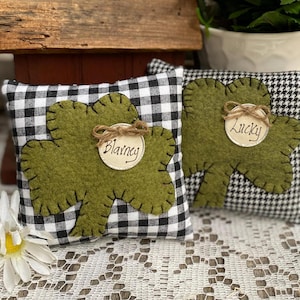 May include: Two green shamrock-shaped pillows with black and white checkered fabric. One pillow says "Blarney" and the other says "Lucky".