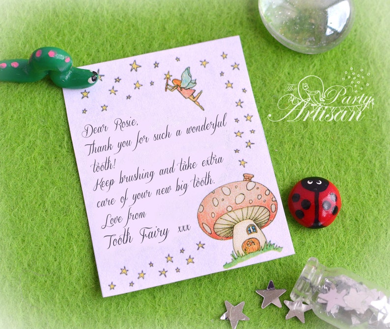 Może przedstawiać: Kapryśna notatka od Wr&oacute;żki Zębuszki, zaadresowana do Rosie, z ilustracją wr&oacute;żki i domkiem z grzyb&oacute;w. W pobliżu znajduje się zielona gąsienica i czerwona biedronka, a także konfetti w kształcie gwiazd.