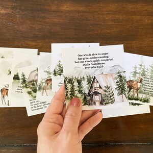 May include: A set of 10 watercolor cards with inspirational quotes and woodland scenes. The cards feature a cabin in the woods, deer, and trees. The quotes include "One who is slow to anger has great understanding" and "Let every person be quick to hear, slow to speak, slow to anger."