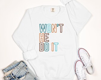May include: White long-sleeve sweatshirt with the text "WON'T HE DO IT" in colorful outlined letters.