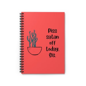 May include: A red spiral notebook with the text "Piss satan off today, sis." and a drawing of a cactus in a pot.