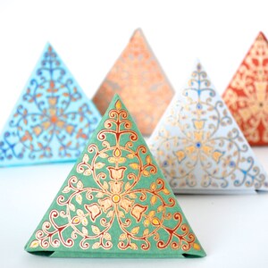 May include: Five triangular boxes with intricate floral patterns in shades of blue, green, orange, and red. The boxes are made of paper and have a decorative, ornate design.