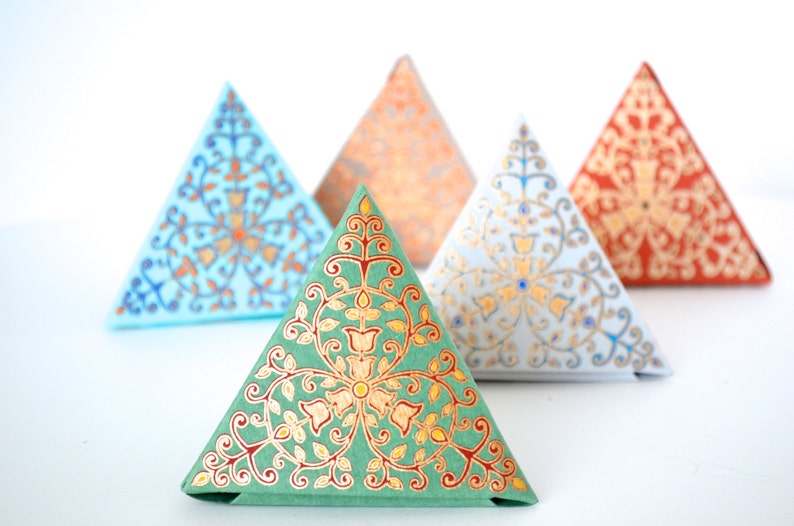 May include: Five triangular boxes with intricate floral patterns in shades of blue, green, orange, and red. The boxes are made of paper and have a decorative, ornate design.
