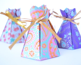 May include: Three small, pyramid-shaped gift boxes with gold ribbon. The boxes are made of paper with a floral pattern. The boxes are blue, purple, and pink.
