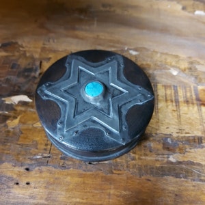 May include: A round wooden box with a silver six-pointed star design and a turquoise stone in the center.