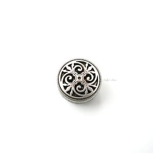 May include: Silver round charm with a decorative filigree design.