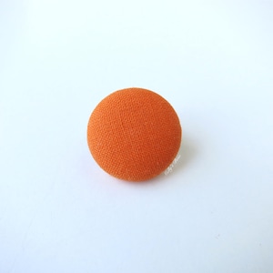 Puede incluir: Un botón redondo de tela naranja.