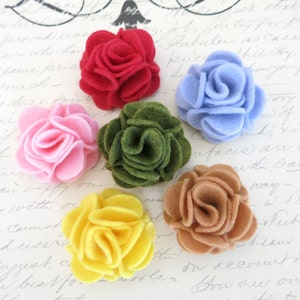 Peut inclure: Six décorations florales en feutre de différentes couleurs, dont le rouge, le rose, le vert, le jaune et le marron. Chaque fleur est composée de plusieurs couches de feutre, créant un effet 3D.