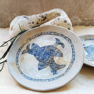 Handcrafted stoneware plate with ash glaze and three hand-drawn fish. Seaside-inspired pottery for multiple uses.