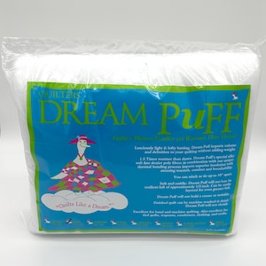 May include: A package of Dream Puff batting for quilting. The package has a blue and green label with the words "Dream Puff" in large letters. The label also features a cartoon goose wearing a hat and a quilt.