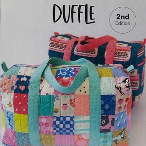 May include: Two patchwork duffle bags with colorful quilted patterns. The front bag has a light blue handle and a patchwork design with strawberries, horses, and other motifs. The text "PATCHWORK DUFFLE" is at the top, with "2nd Edition" in a circle. The logo "KNOT + THREAD design" is at the bottom.