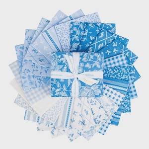 May include: A collection of blue and white fabric squares arranged in a circular pattern. The fabrics feature various floral, bow, and geometric designs. A square bundle of fabric is tied with a white ribbon, with text visible on the ribbon and the bundle.
