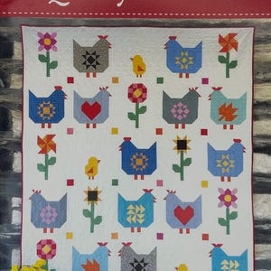 May include: A white quilt with a repeating pattern of colorful chickens, flowers, and small birds. The quilt measures 72.5 inches by 82.5 inches. The text "Quilty Chicks" is at the top.