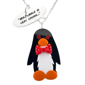 May include: A black and white penguin with a red bow tie and orange feet hangs from a silver chain. A white speech bubble with the text "MR. FLIBBLE IS VERY CROSS..." hangs above the penguin.