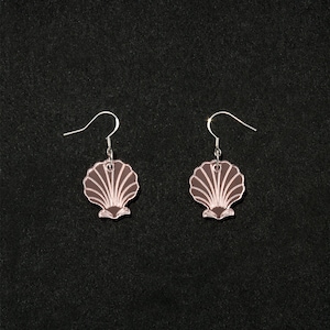 May include: A pair of silver earrings with a pink seashell design. The seashells are detailed with lines and a small indentation at the bottom.